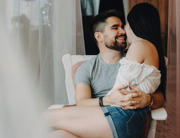 A girl sitting on a guy's lap and he laughs and they show some of these flirting signs.