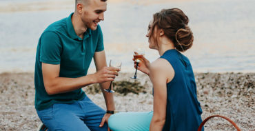 A man and a woman on their first date, having a picnic on the beach and wondering what comes after the first date.