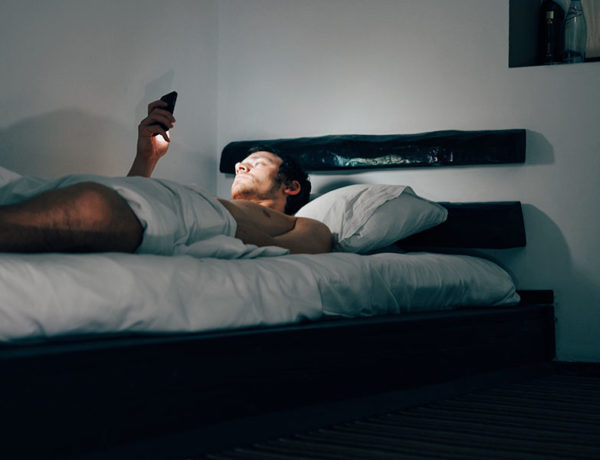 A guy in bed at night going through his Tinder top picks.