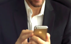 A guy double texting a girl and showing how guys text when they like you while wearing a nice suit and smiling.