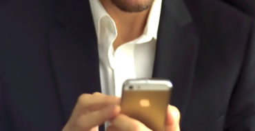 A guy double texting a girl and showing how guys text when they like you while wearing a nice suit and smiling.