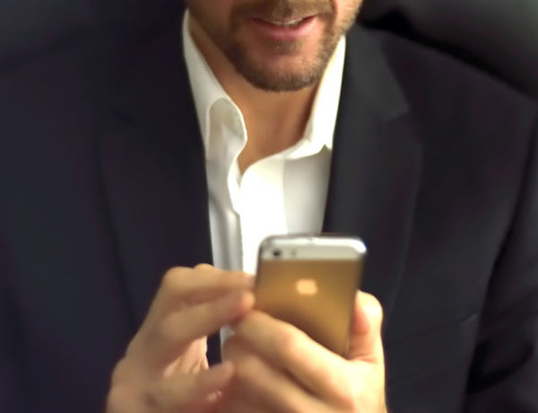 A guy double texting a girl and showing how guys text when they like you while wearing a nice suit and smiling.
