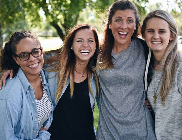 Four girls who are different types of friends, all hugging and laughing together.