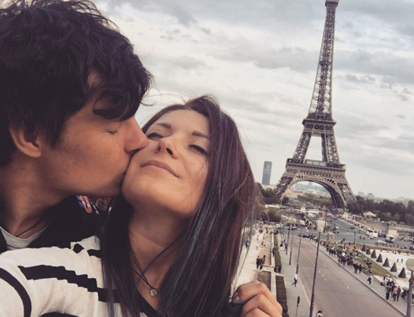 A couple who met international dating, kissing in front of the Eiffel tower.