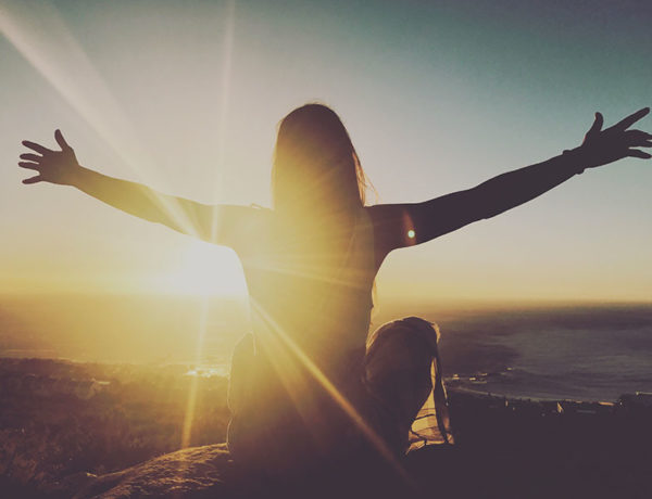 A woman on a mountain embracing the universe and the concept of agape love.