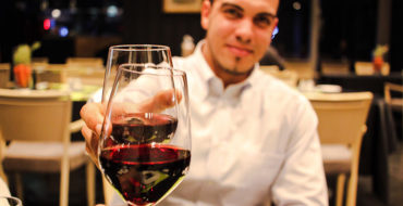 A guy on a first date cheersing his date across the table.