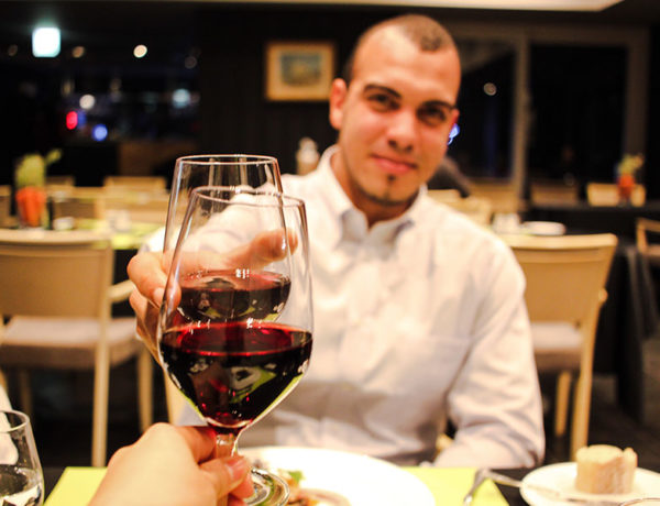 A guy on a first date cheersing his date across the table.