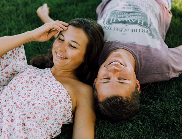 A guy who used one of these creative first date tips, laughing in the grass with his date.