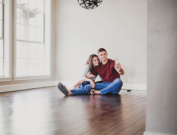 A couple moving in together taking a selfie on the floor of their new apartment.