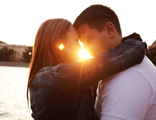 A couple in a love hate relationship kissing in front of the sunset.