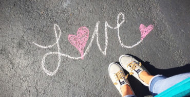 A girl looking down at her shoes and a single life quote that says love written at her feet.