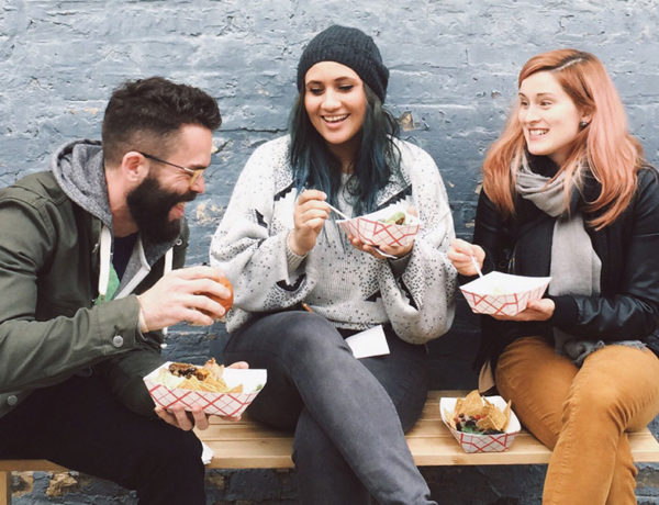 A group who learned how to find friends online laughing and eating together outside.