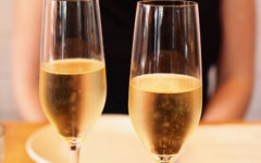 A woman sitting in front of two champagne glasses who took this first date advice to relax and keep it to one drink.