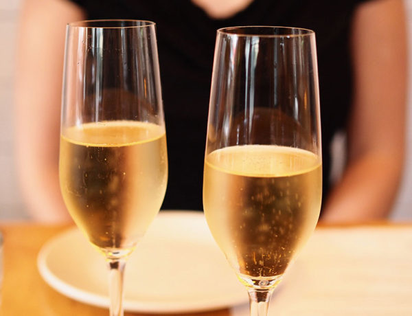 A woman sitting in front of two champagne glasses who took this first date advice to relax and keep it to one drink.