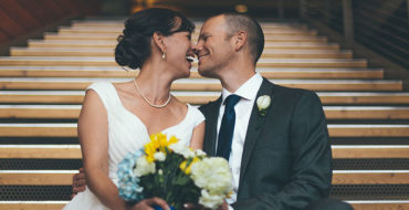 A couple who learned a thing or two from these true love quotes, sitting on the church steps on their wedding day touching noses and laughing together.