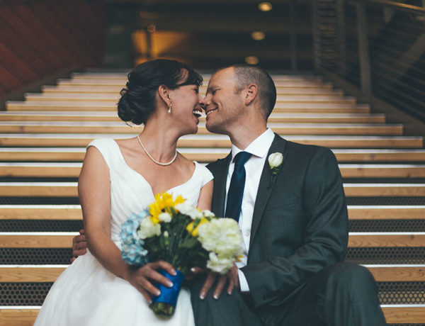 A couple who learned a thing or two from these true love quotes, sitting on the church steps on their wedding day touching noses and laughing together.