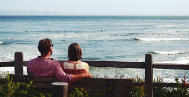 A couple talking about the man's ex while sitting on a bench.