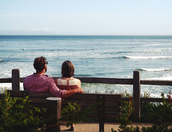 A couple talking about the man's ex while sitting on a bench.