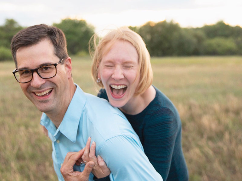 A man over 40 who's never been in a relationship before, laughing with his girlfriend in a field as he learns how to navigate his way through it.