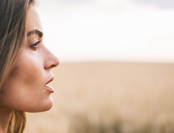 A woman who's battling with codependency standing in a field thinking.