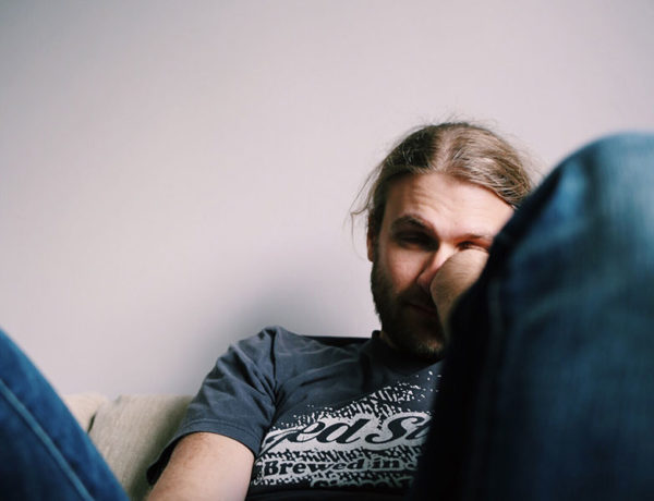 A guy thinking "I have no friends," while slouching on his couch looking sad.