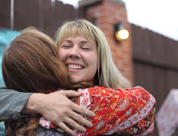 Two friends that know that friends come and go, hugging and laughing as they greet each other.