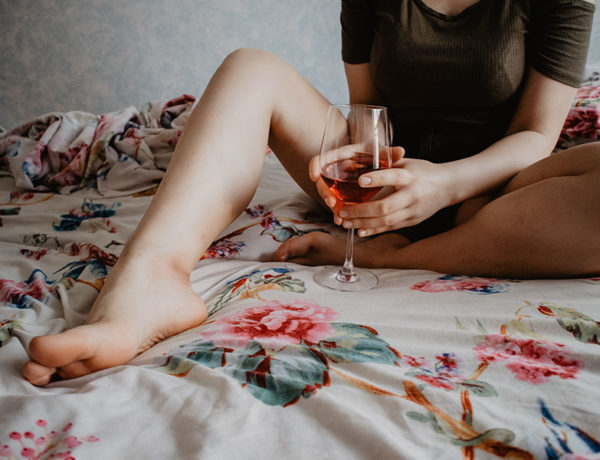A woman who's alone on a Friday night, drinking wine in bed.