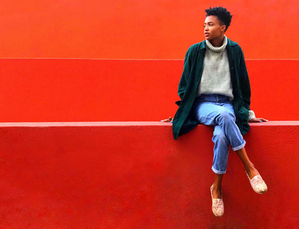 A woman who was thinking of giving up on love, sitting in front of a red wall thinking about how she feels.