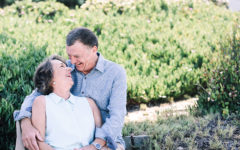 A couple dating over 60 smiling at each other while hugging in a garden.