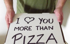 A man holding a pizza box that says, "I heart you more than pizza." One of the romantic gestures for her that will make her day.