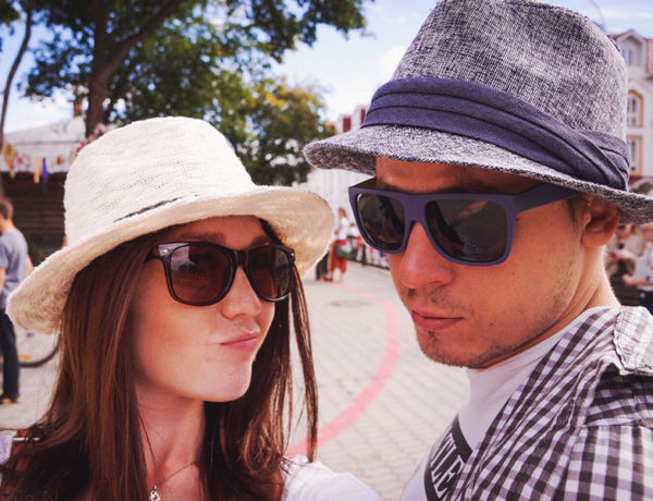 A girl with her guy best friend, making a funny face while wearing similar hats and sunglasses.