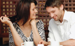 A man who took these flirting tips for guys, talking to a woman at a coffee shop who's laughing at his jokes.