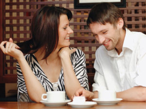 Un homme qui a pris ces astuces pour les gars flirter, parler à une femme dans un café qui se moque de ses blagues.