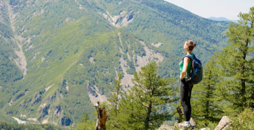 A woman who's taking time for herself after a breakup on a solo hike looking out at the view of the mountains.