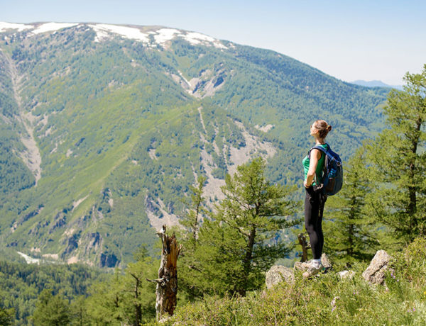 A woman who's taking time for herself after a breakup on a solo hike looking out at the view of the mountains.