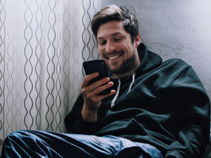Un gars à la recherche d'applications plus doué que Tinder, souriant alors qu'il discute avec une fille sur une nouvelle application.