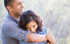 A man who is a jealous boyfriend hugging his girlfriend tight as they laugh together.