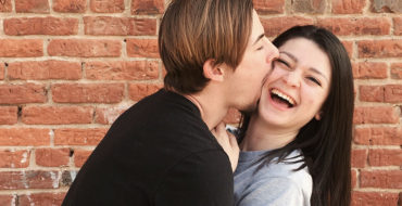 A woman laughing at her boyfriend's corny pickup lines.