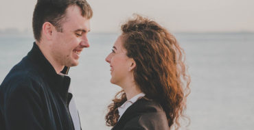 A guy using one of these flirty conversation starters looking at a woman on the beach and smiling.