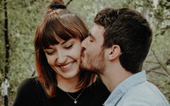 A guy kissing the cheek of his jealous girlfriend, and explaining she has nothing to worry about.