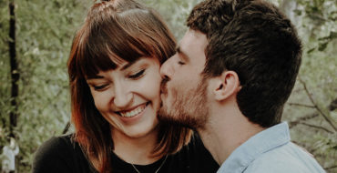 A guy kissing the cheek of his jealous girlfriend, and explaining she has nothing to worry about.