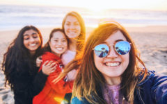 A group of girls who met on a Tinder for friends app, at the beach smiling as they take a picture.