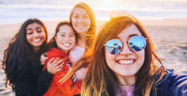 A group of girls who met on a Tinder for friends app, at the beach smiling as they take a picture.