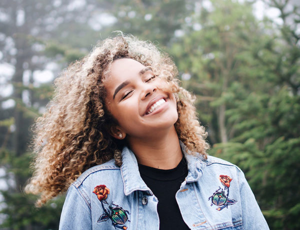 A woman who learned to love yourself first, smiling and laughing at the sky.