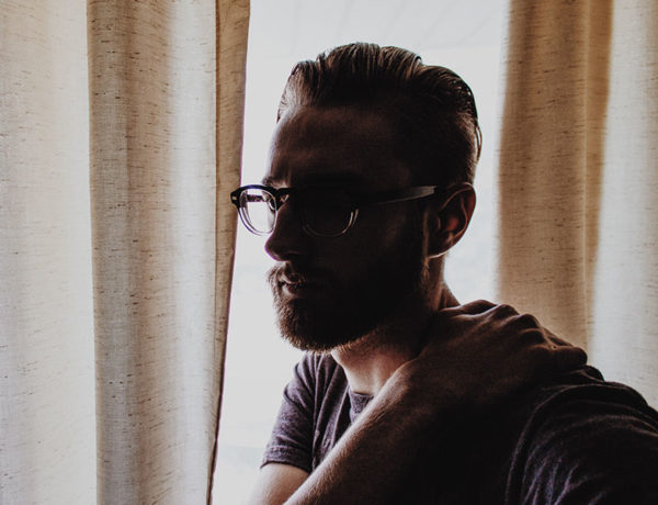 A man who's seen the signs that it's time to break up thinking and looking stressed out a window.