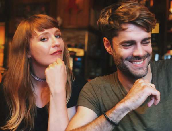 A woman who's feeling jealousy in an open relationship giving her boyfriend a doubtful look while they're at the bar together.