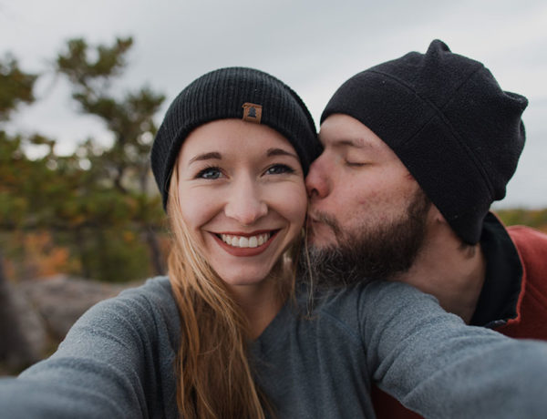 A couple who used to be in a situationship, smiling as the guy kisses the girl's cheek while hiking.
