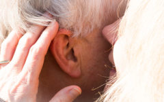 A woman whispering in her dates ear, after listening to some of these senior dating tips.
