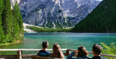 Four people in a quad relationship hanging out on a bench in front of a beautiful lake.