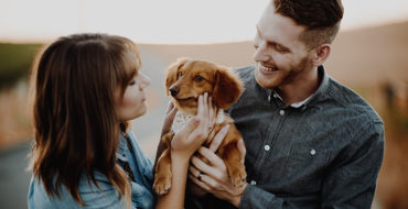 A couple in a good relationship smiling and laughing with their dog.